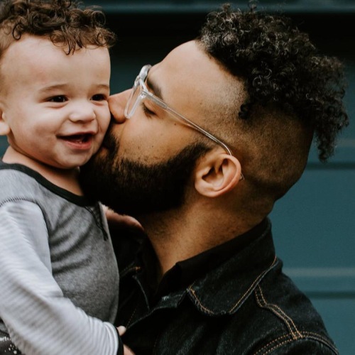 father holds and kisses his toddler son